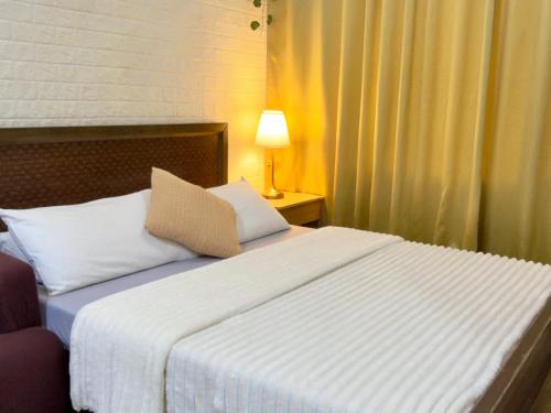 a bedroom with a large white bed with a lamp at Hannah’s Morning Sun - Studio Room in Manila