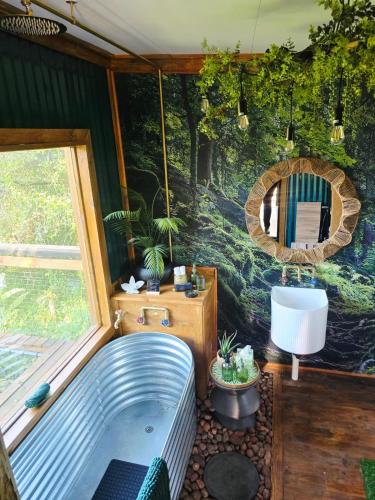 a bathroom with a tub in front of a wall at Tin Town Glamping in Haenertsburg