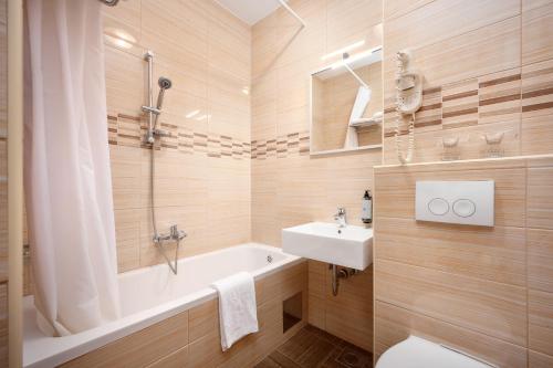 a bathroom with a tub and a sink and a toilet at Hotel Zora in Primošten