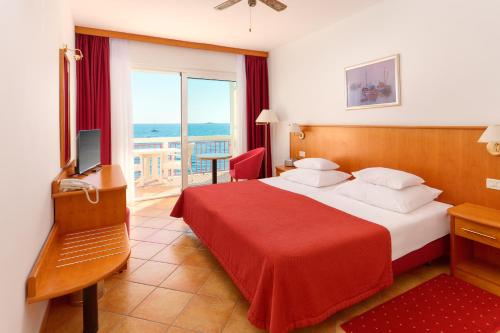 a hotel room with a bed with a red blanket at Hotel Zora in Primošten