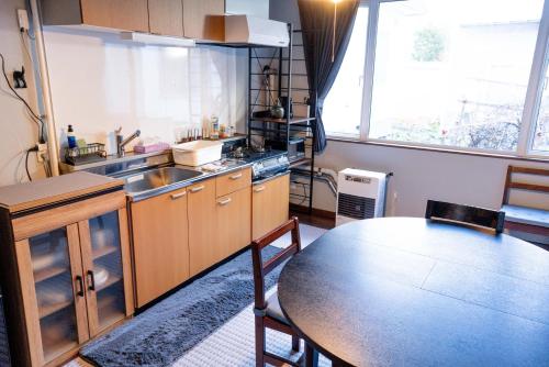 a kitchen with a table and a sink and a table at SNS guest house Sapporo in Sapporo