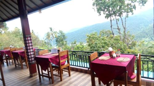 a balcony with tables and chairs with mountains in the background at Aris Homestay and Warung Made in Munduk