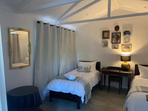 a bedroom with two beds and a desk with a mirror at Desert Bloom Cottage in Buffelskloof
