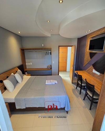 a bedroom with a bed and a table and a television at Barueri Premiêr Hotel in Barueri