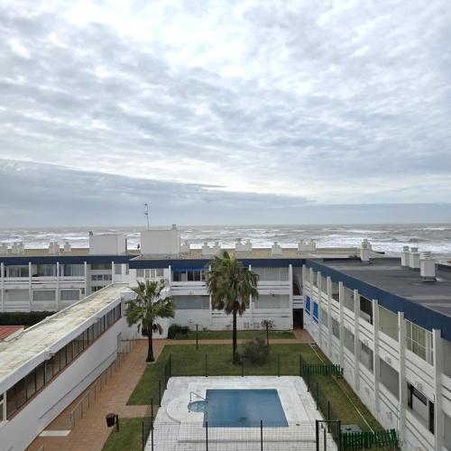 an apartment building with a swimming pool and the ocean at Hilo Verde in Matalascañas