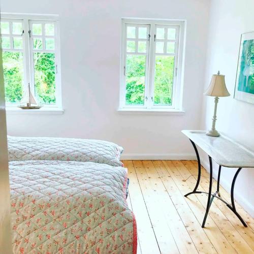 a bedroom with a bed and a table and windows at Farmhouse in idyllic settings in Ærøskøbing