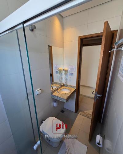 a bathroom with a toilet and a sink and a mirror at Barueri Premiêr Hotel in Barueri