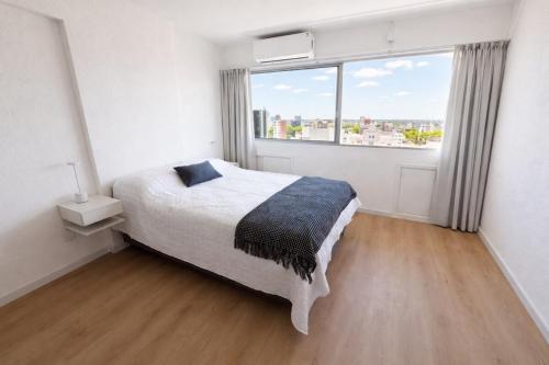 a bedroom with a bed and a large window at Monoambiente amplio , moderno y super completo in Montevideo