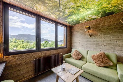 a room with a couch and a table and windows at Les Loges Du Parc in Gérardmer