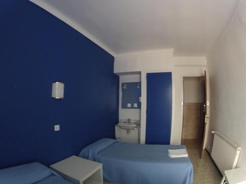 a blue room with a bed and a table at Hostal German in Port de la Selva