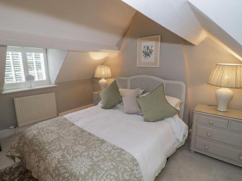 a bedroom with a bed and two lamps and a window at Bumblebee Cottage in Tetbury