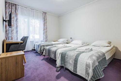 two beds in a room with a tv and a window at Resort Niegocin in Wilkasy
