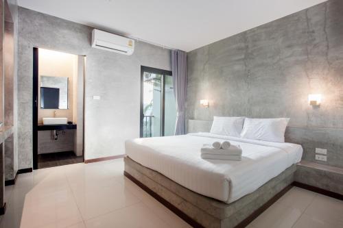 a bedroom with a large white bed with towels on it at Ritsurin Boutique Hotel - โรงแรมริทสุริน บูติค in Phuket