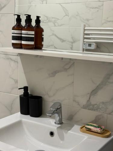 un lavabo de salle de bain avec trois bouteilles sur une étagère dans l'établissement T2 Near CDG Bourget, à Le Thillay