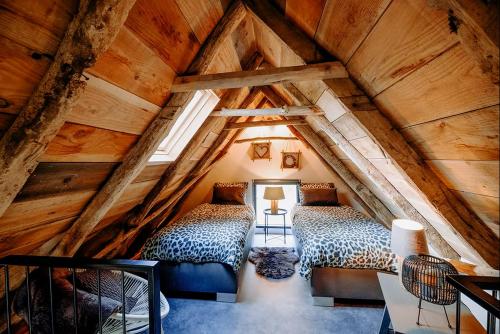 two beds in a attic room with wooden ceilings at Vakantiewoning Lemselermaten in Weerselo