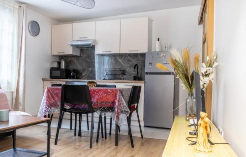 une cuisine avec des armoires blanches et une table avec des chaises dans l'établissement T2 Near CDG Bourget, à Le Thillay