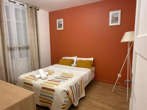 une chambre avec un lit aux murs orange dans l'établissement T2 Near CDG Bourget, à Le Thillay