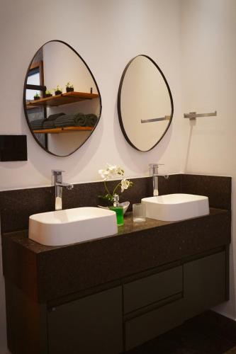 a bathroom with two sinks and two mirrors at Recanto do Guará Cabana in Capitólio