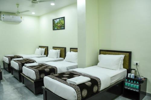 a group of four beds in a room at Ganga Regency in Solapur