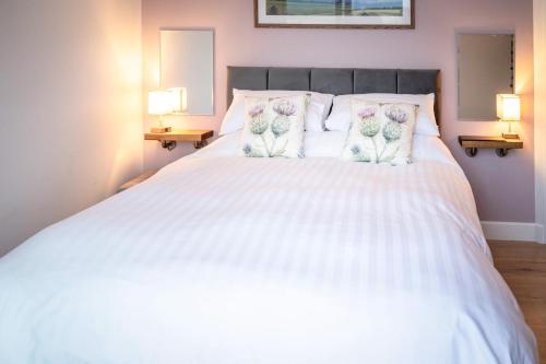 a bedroom with a white bed with flowers on the pillows at Bennachie Lodge in Huntly