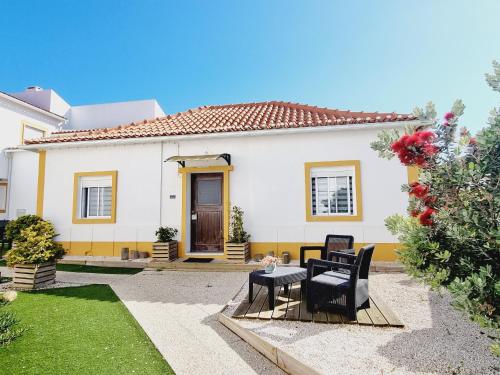 a white house with two chairs and a table at Family Surf Home - Casas do Páteo in Ribamar