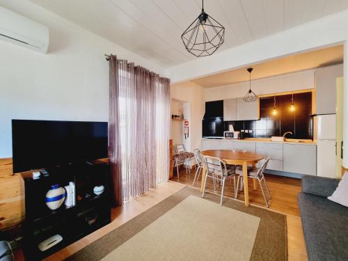 a living room with a table and a kitchen at Family Surf Home - Casas do Páteo in Ribamar