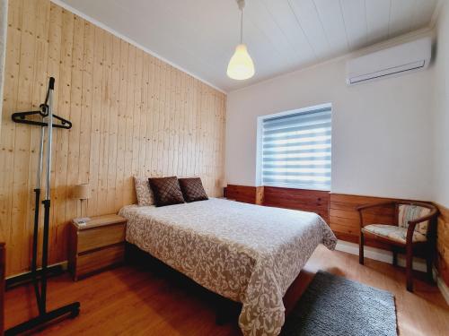 a bedroom with a bed and a chair and a window at Family Surf Home - Casas do Páteo in Ribamar