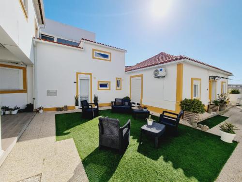 a patio with chairs and a yard with green grass at Family Surf Home - Casas do Páteo in Ribamar