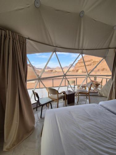 a bedroom with a bed and a view of the desert at Sofia Bubble Luxury Camp in Disah