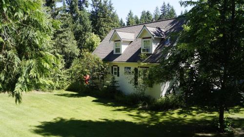 a house in a yard with a green lawn at The Inn at the Ninth Hole Bed & Breakfast in Salmon Arm