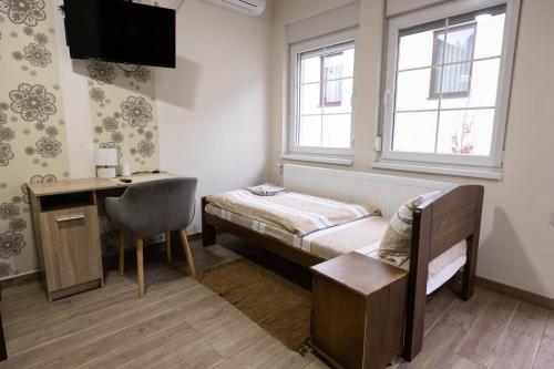 a bedroom with a bed and a desk and window at Zlatni Klas in Zrenjanin