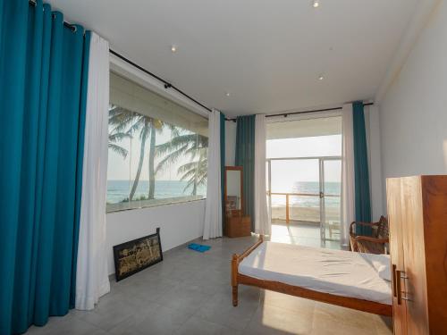 a bedroom with a bed and a view of the ocean at Kavin Beach Hotel Hikkaduwa in Hikkaduwa