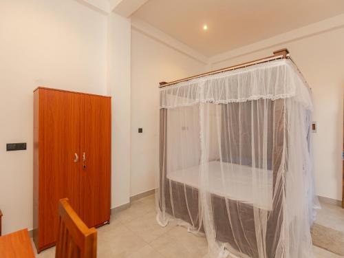 a room with a curtain and a wooden cabinet at Kavin Beach Hotel Hikkaduwa in Hikkaduwa