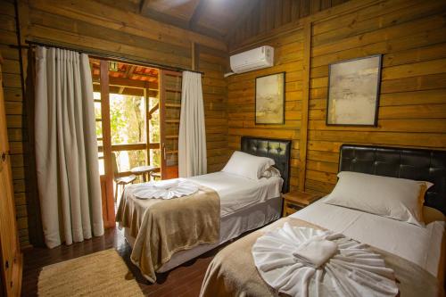 two beds in a room with wooden walls at Pousada Fazenda Caetés in Camboriú