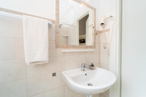 a white bathroom with a sink and a mirror at Amadei Hotel Blumen in Pesaro