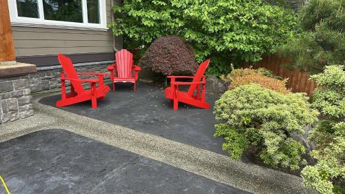 three red chairs and a table in front of a house at Large ocean view family retreat in Comox
