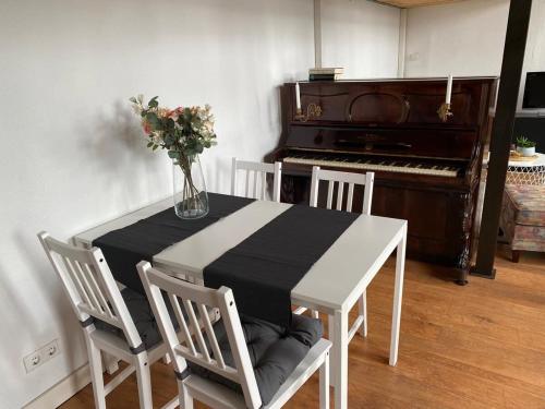 a table with a vase of flowers and a piano at Modernes City-Apartment in Krefeld - BEUYS Apartments Krefeld in Krefeld