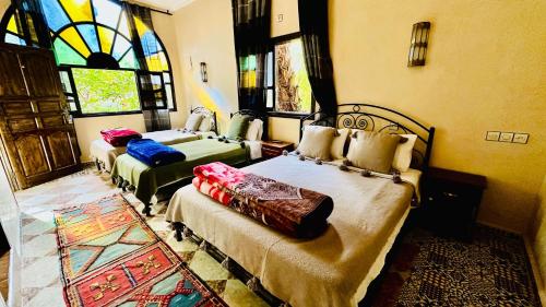 a bedroom with two beds and a stained glass window at Chez Ali Zagora Authentic Hotel Restaurant and Desert Excursions in Zagora