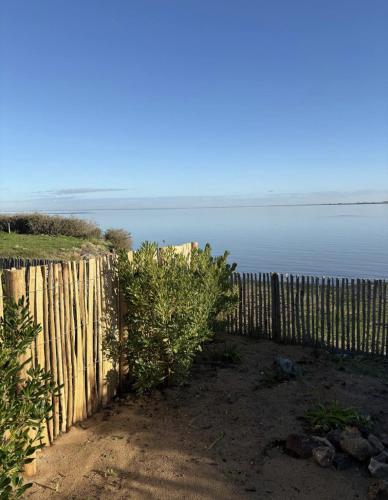 a wooden fence next to a body of water at L'escale les pieds dans l'eau in Barbâtre