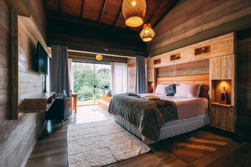 a bedroom with a bed and a large window at Pousada Trem Chic in Poços de Caldas