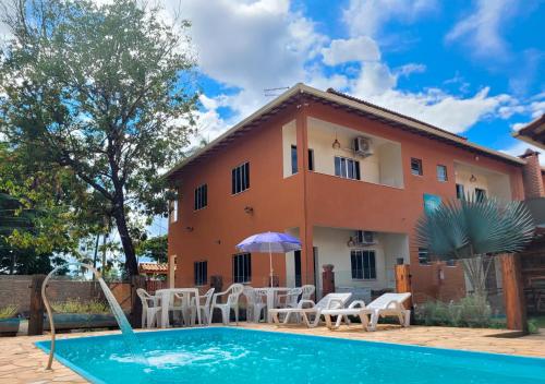 a villa with a swimming pool in front of a house at Pousada Flor do Campo in Serra do Cipo