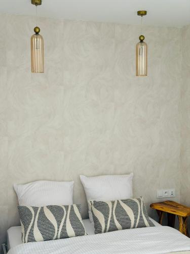 a bedroom with a bed with two pillows and two lights at Nowoczesne Domki na Łące - Sauna & Balia & Jacuzzi - PolanaGlamp in Nieżyn