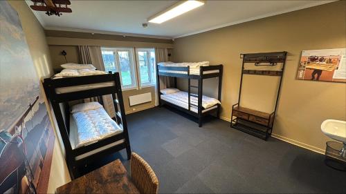 a room with three bunk beds and a sink at Stayover Lista in Farsund