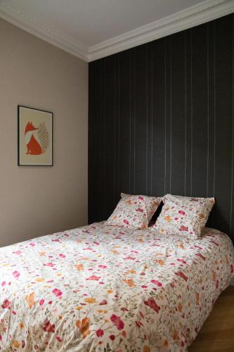 a bedroom with a bed with a floral bedspread at Au bonheur de Troyes in Troyes