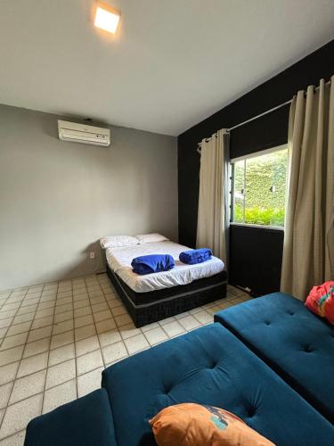 a bedroom with a bed and a couch and a window at Garden Room Comfort in Garanhuns