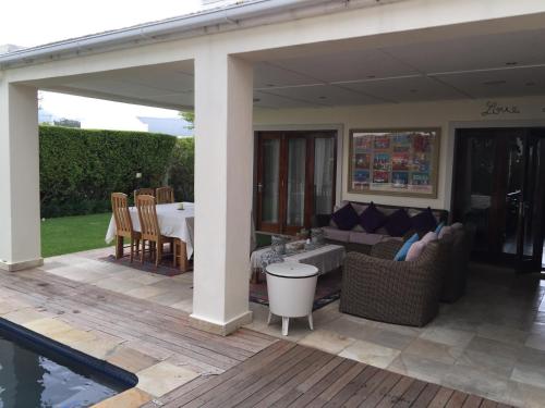 Un patio con mesa y sillas y una piscina. en De Zalze Luxury Lodge, en Stellenbosch