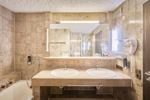 a bathroom with two sinks and a tub at Luna Inn Stuttgart City in Stuttgart
