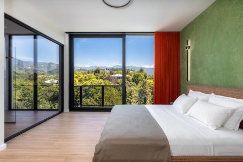 a bedroom with a large bed and large windows at Gantiadi Holiday - Pool and Houses in Batumi