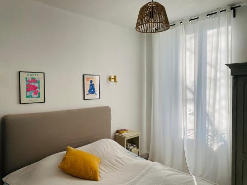 a bedroom with a bed with a yellow pillow and a window at Gîte Mas La Bohème Piscine Parking Privé L'Isle-Sur-La-Sorgue in L'Isle-sur-la-Sorgue