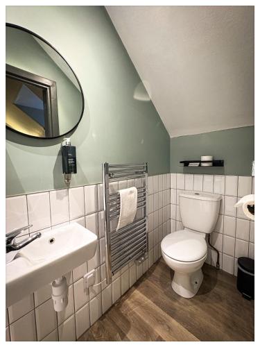 a bathroom with a toilet and a sink and a mirror at The Balavoulin - Pub with Rooms in Aviemore